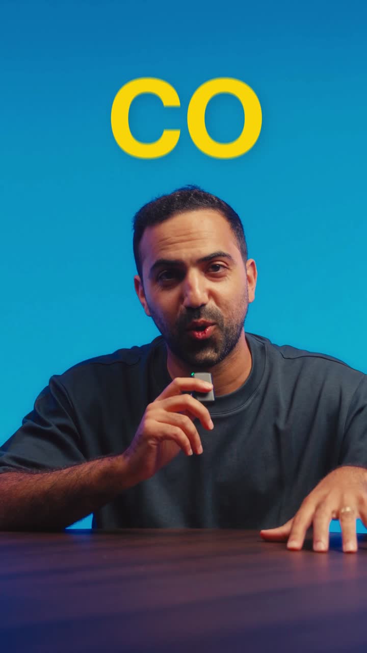 Amin Hamzianpour speaking into a microphone against a blue backdrop